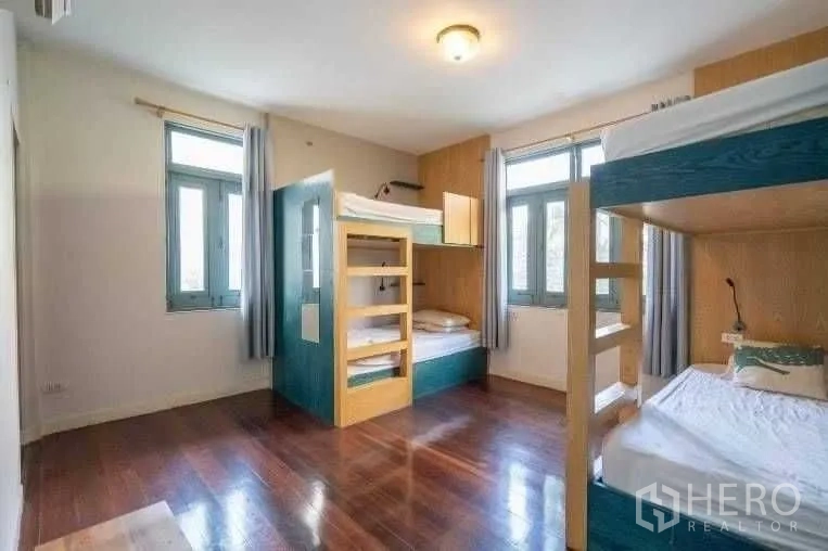 Detached House for rent in Khlong Toei, Bangkok - Spacious bedroom with multiple bunk beds and corner windows for natural light.