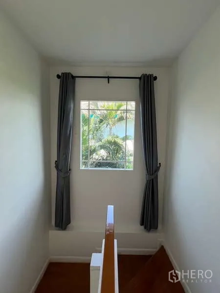 Detached House for rent in Bang Kapi, Bangkok - Stair landing with curtained window and leafy garden outlook.