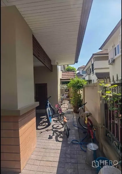Detached House for sale in Bang Yai, Nonthaburi - Side walkway of the house with bicycles and utility area.