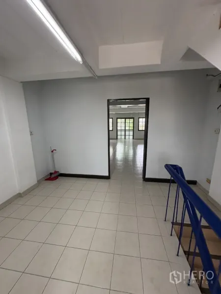 Shophouse for rent in Phra Khanong, Bangkok - Stair landing with blue handrail opening to a light‑filled workspace.
