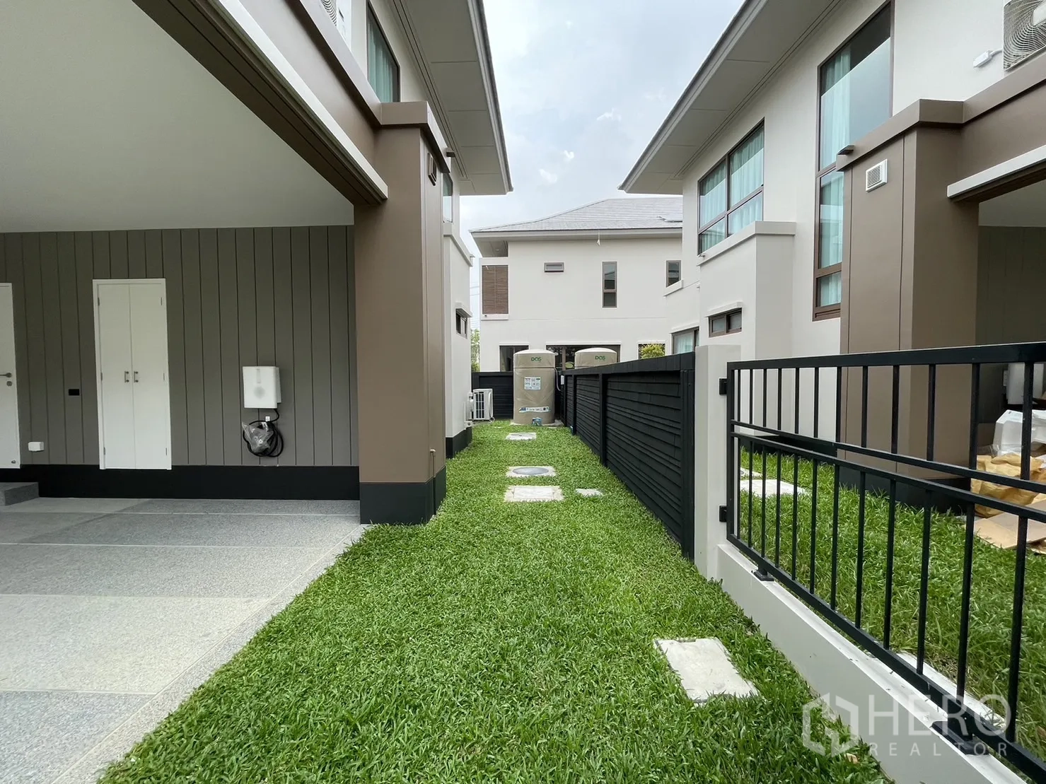 Detached House for rent in Bang Kapi, Bangkok - Side yard with green lawn, fence, and covered carport.