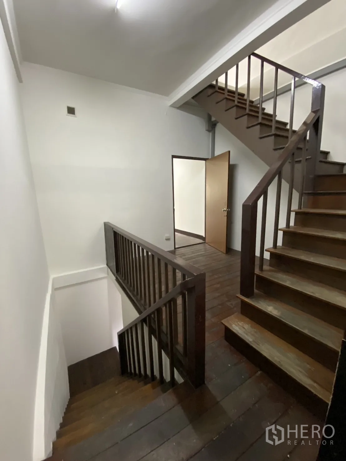 Shophouse for rent - Central staircase with dark wooden steps and rails connecting multiple floors.
