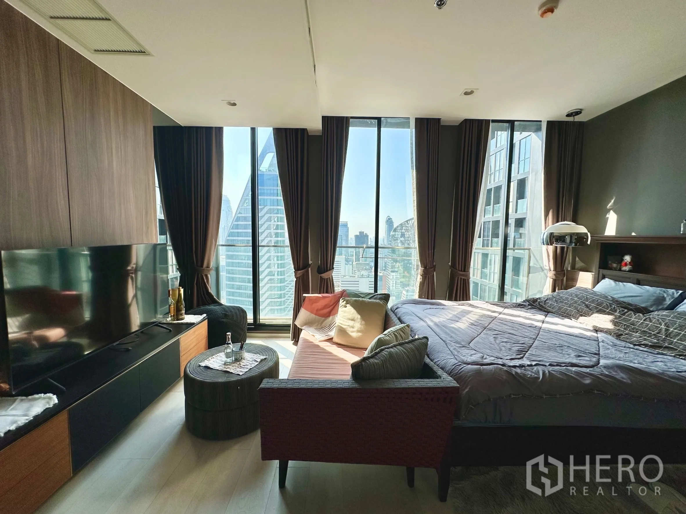 Condominium for rent in Pathum Wan, Bangkok - Bedroom with large TV wall, panoramic windows and city views.