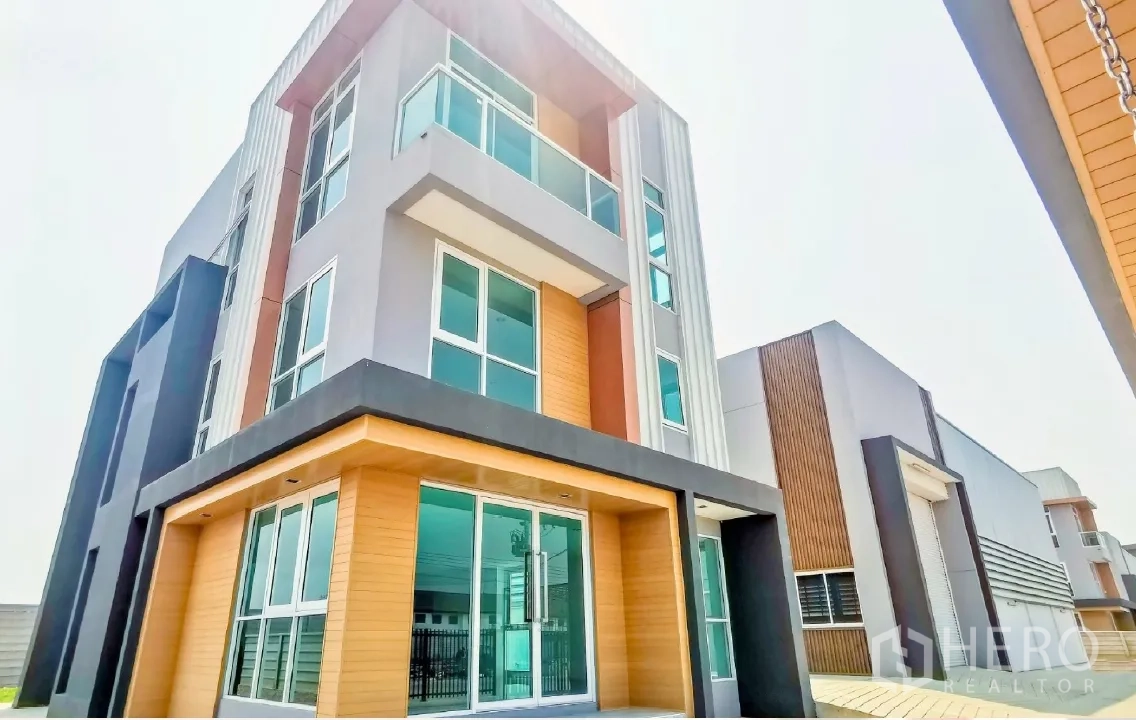 Warehouse for sale in Lam Luk Ka, Pathum Thani - Modern three-storey home office facade with large windows and glass balconies in an industrial estate.