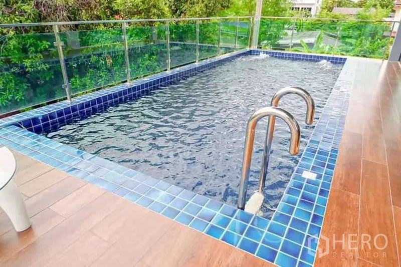 Detached House for sale in Lat Phrao, Bangkok - Close-up of raised blue-tiled private swimming pool with stainless ladder and glass railing.
