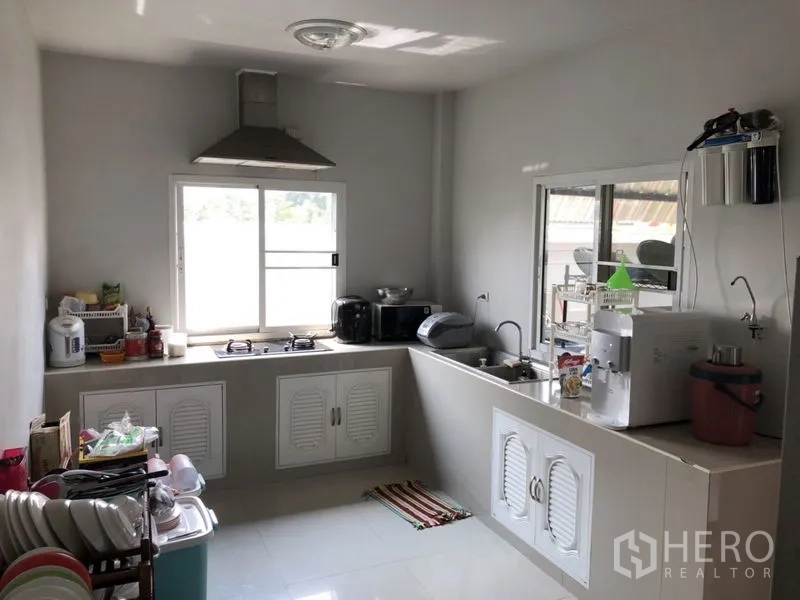 Detached House for sale in Lam Luk Ka, Pathum Thani - Light-filled kitchen with L-shaped countertop, hob and range hood.