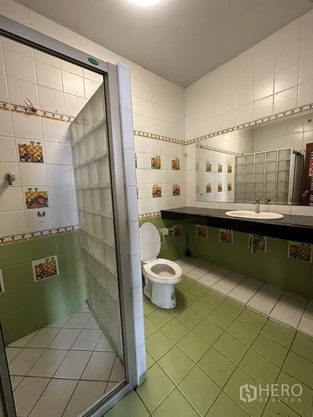 Detached House for rent in Phaya Thai, Bangkok - Tiled bathroom with glass-block shower, long vanity and toilet.