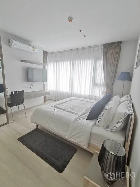 Condominium for rent in Pathum Wan, Bangkok - Sunlit bedroom with double bed, desk and wall-mounted TV.