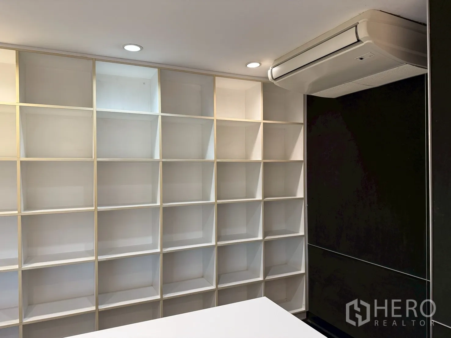 Office Space for rent in Huai Khwang, Bangkok - Wall of square open shelves beside a dark feature wall and ceiling AC unit.