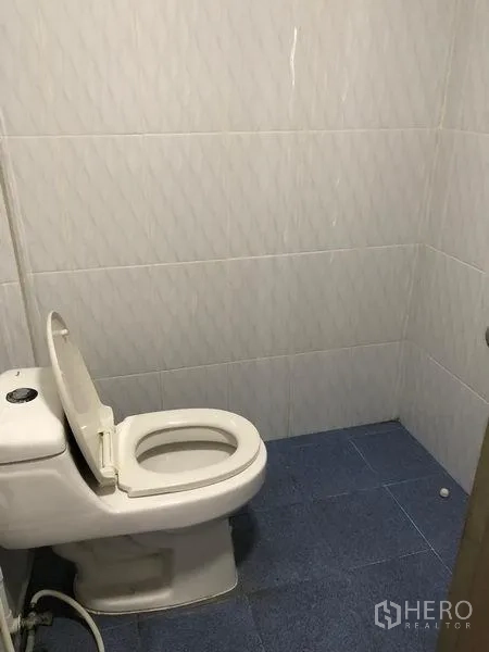 Warehouse for rent in Pak Kret, Nonthaburi - Clean tiled restroom with a toilet inside the warehouse.