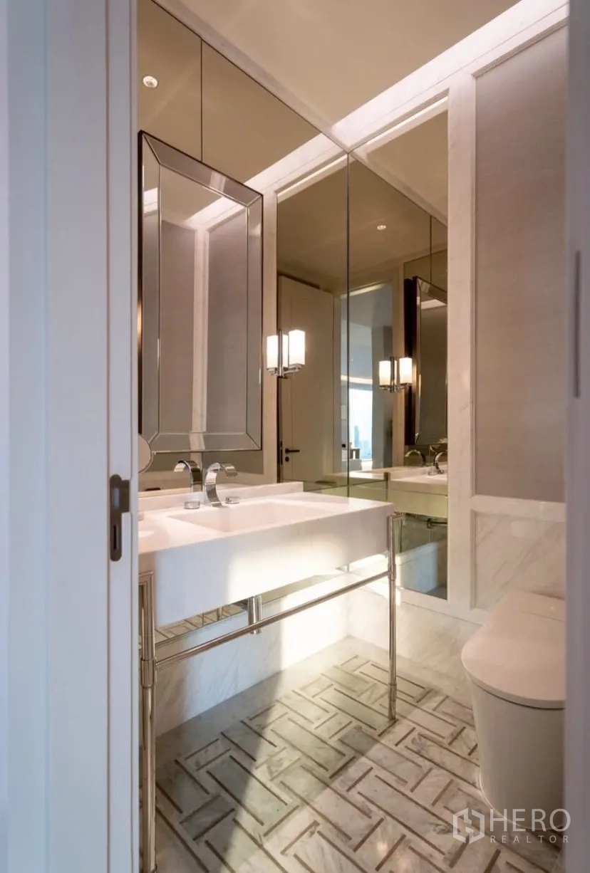 Condominium for rent or sale in Pathum Wan, Bangkok - Powder room with wall mirrors, white vanity and modern toilet on marble flooring.