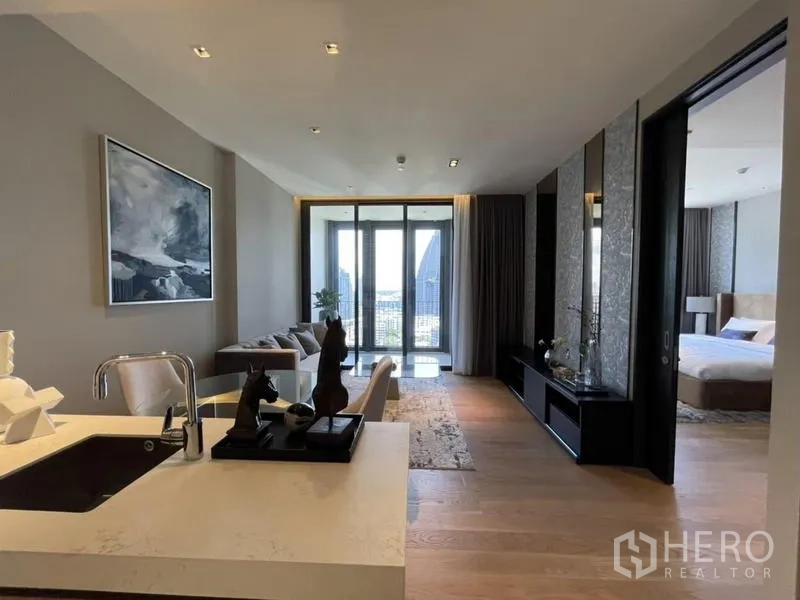 Condominium for rent in Khlong Toei, Bangkok - View from kitchen toward living area and balcony, with bedroom doorway visible and city vistas beyond.