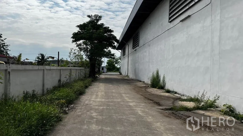 Factory for rent or sale in Pathum Thani - Side access road running along the factory wall and boundary fence.
