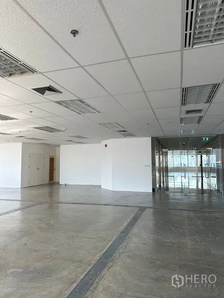 Office Space for rent in Pathum Wan, Bangkok - Spacious office interior with drop ceiling, fluorescent lights and glass entry doors.