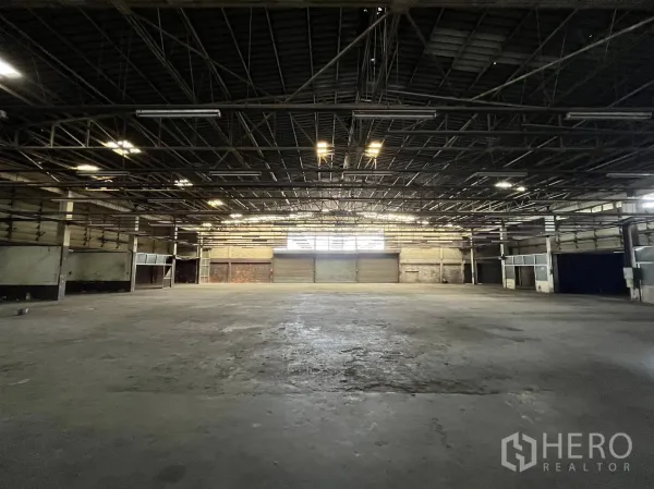 Factory for rent in Phra Pradaeng, Samut Prakan - Expansive factory floor with multiple loading bays and industrial lighting.