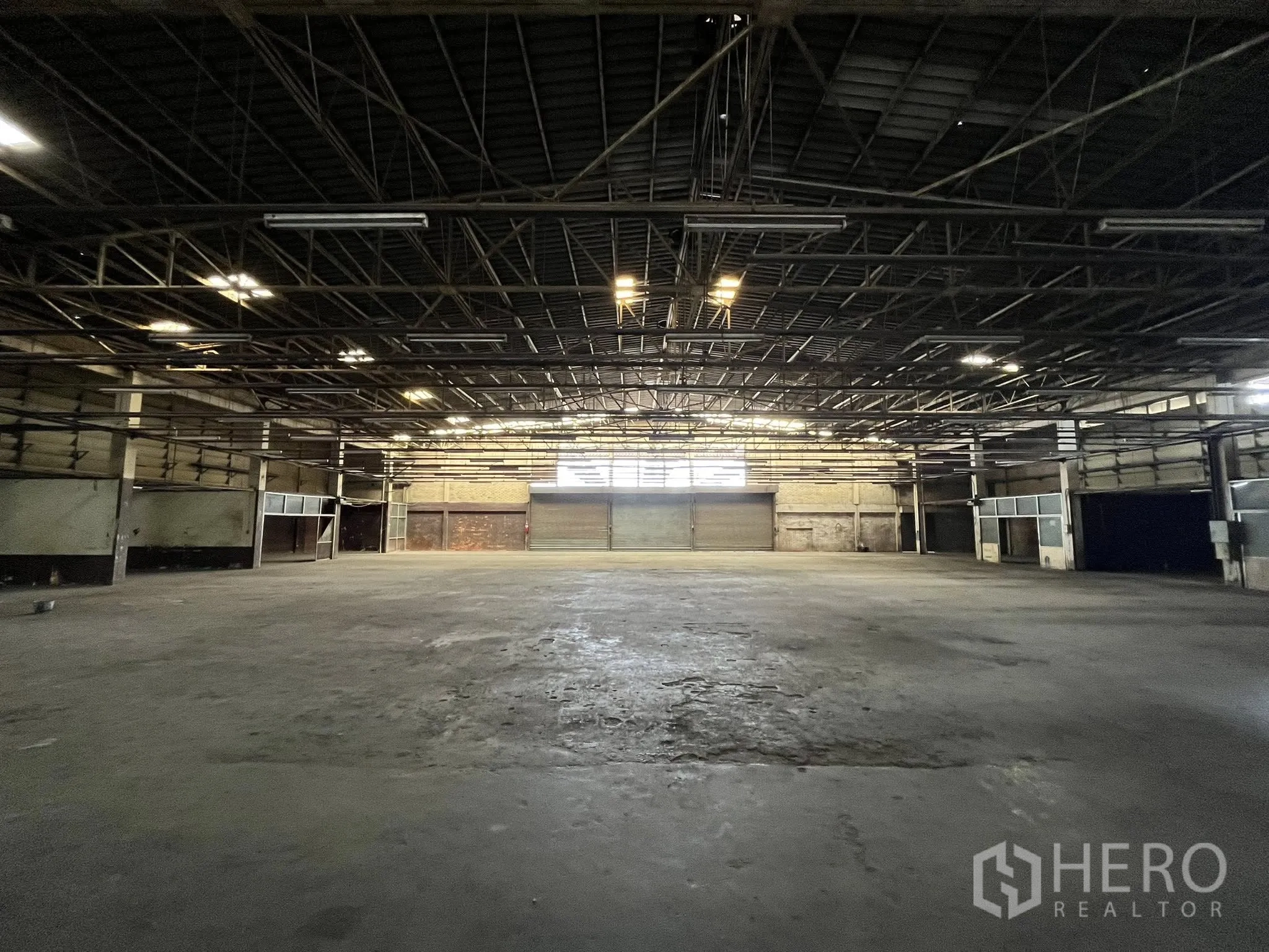 Factory for rent in Phra Pradaeng, Samut Prakan - Expansive factory floor with multiple loading bays and industrial lighting.