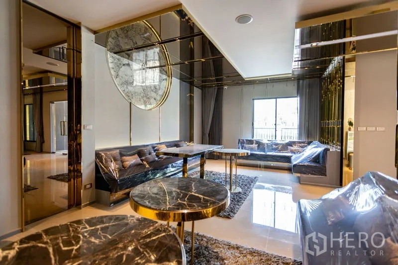 Townhouse for rent in Bang Phli, Samut Prakan - Open-plan living and dining space with marble-topped tables and reflective gold finishes.