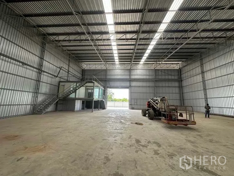 Factory for rent in Wang Noi, Phra Nakhon Si Ayutthaya - Wide interior view toward the loading door, showing steel trusses and equipment.