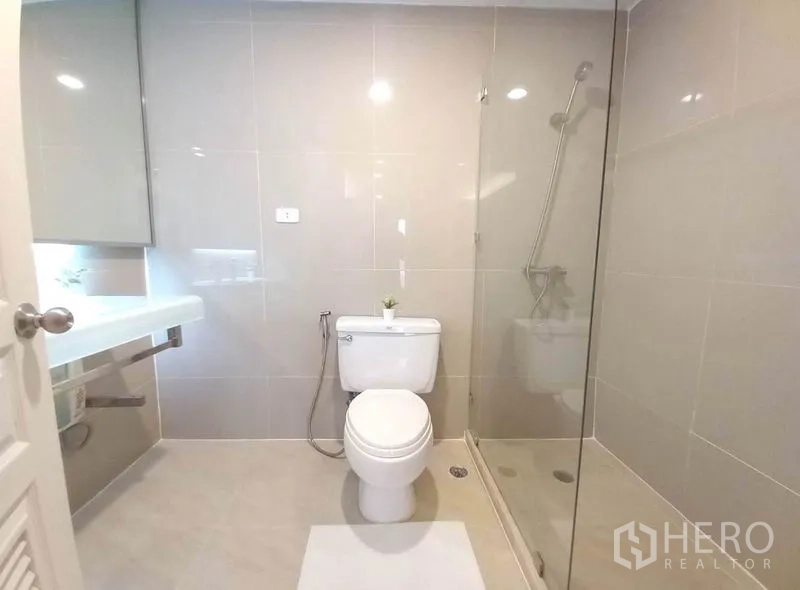 Condominium for rent in Khlong Toei, Bangkok - Second bathroom with walk-in glass shower and neutral tiles.
