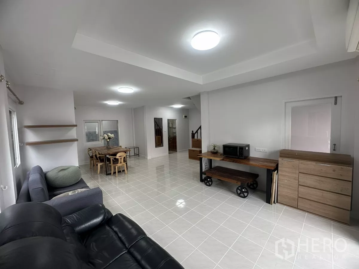 Townhouse for sale in Lam Luk Ka, Pathum Thani - Open living–dining space with media console and wood furniture.