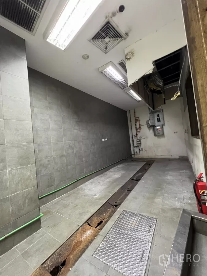Retail Space for rent - Tiled kitchen area featuring a trench drain, ceiling vents and access hatch.