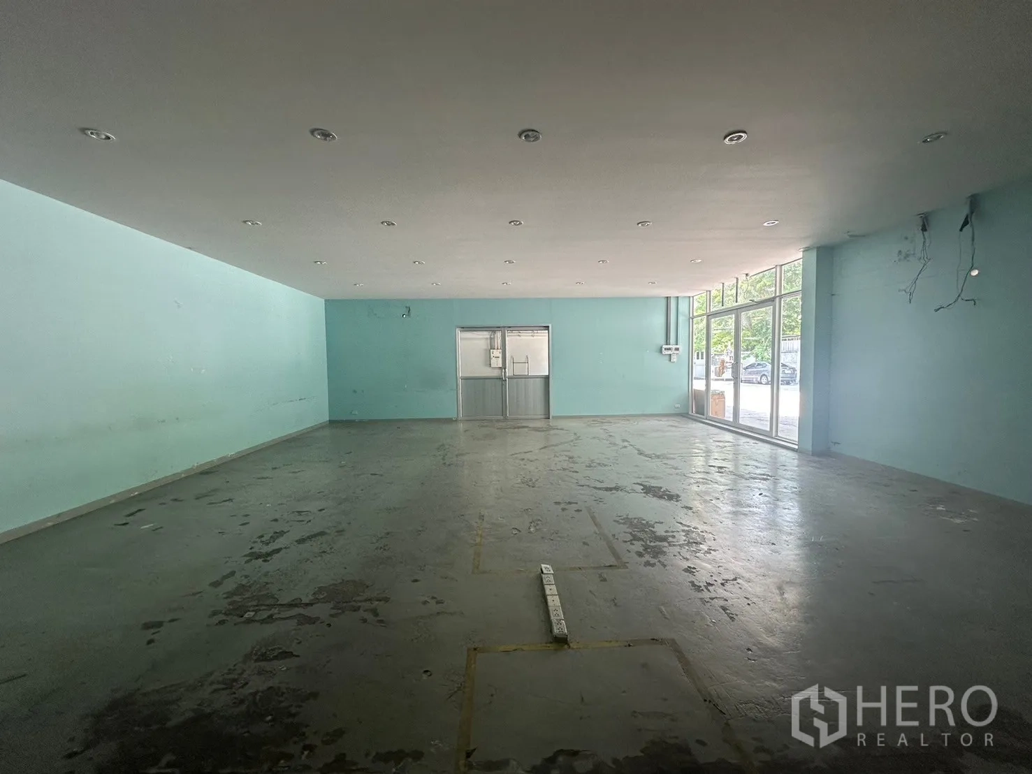 Warehouse for rent in Din Daeng, Bangkok - Showroom space with floor-to-ceiling windows and double glass doors opening to the yard.