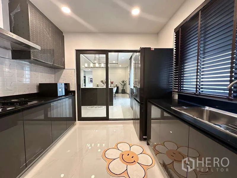 Detached House for rent in Bang Phli, Samut Prakan - Modern kitchen with glossy cabinets, black countertops and sliding glass door.