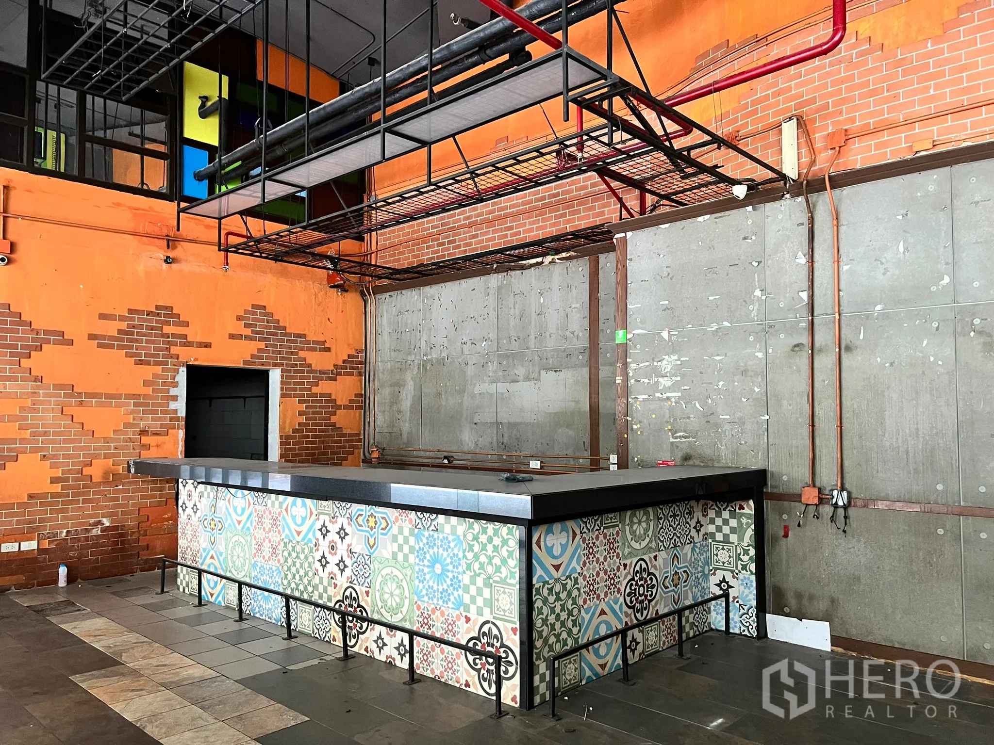 Retail Space for rent in Watthana, Bangkok - Industrial-style retail interior with patterned tile bar counter, exposed pipes, and brick and concrete walls.