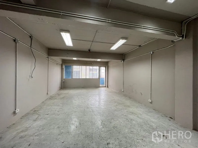Shophouse for rent - Empty back room with fluorescent lights, power outlets and a window.