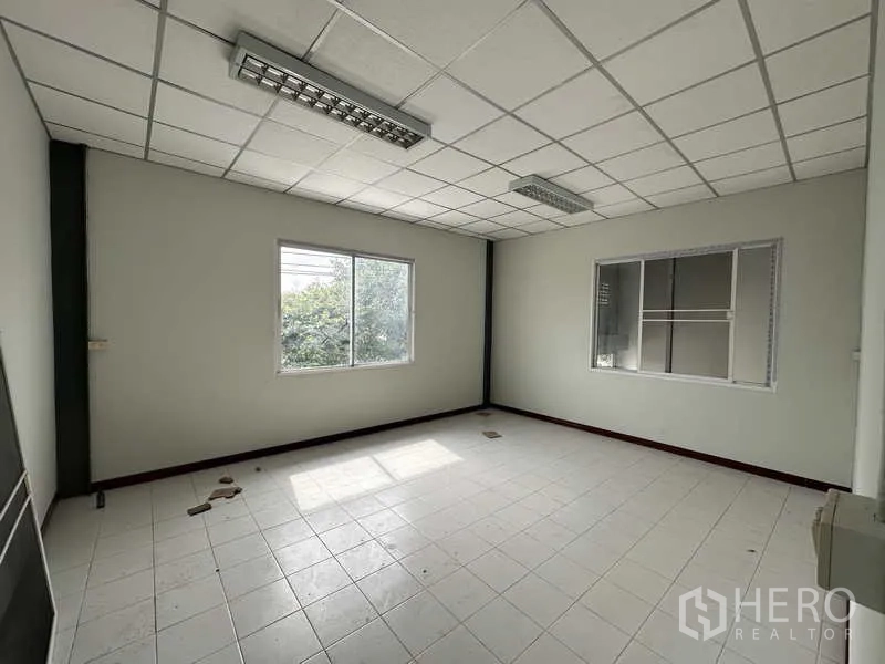 Warehouse for rent in Pak Kret, Nonthaburi - Upstairs office room with large windows and grid ceiling overlooking greenery.