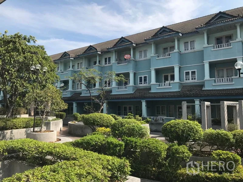 办公空间 出租在Khlong Toei, Bangkok - 低层蓝色建筑外立面，配有绿化庭院和植被。
