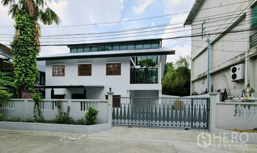 Home Office for rent in Lat Phrao, Bangkok - Street view of a renovated white home office with gated driveway and clerestory windows in Lat Phrao.