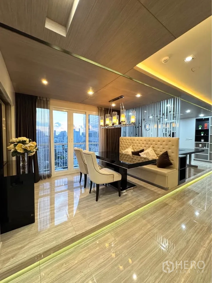 Condominium for rent or sale in Khlong Toei, Bangkok - Dining corner facing a city-view balcony with a contemporary chandelier at dusk.