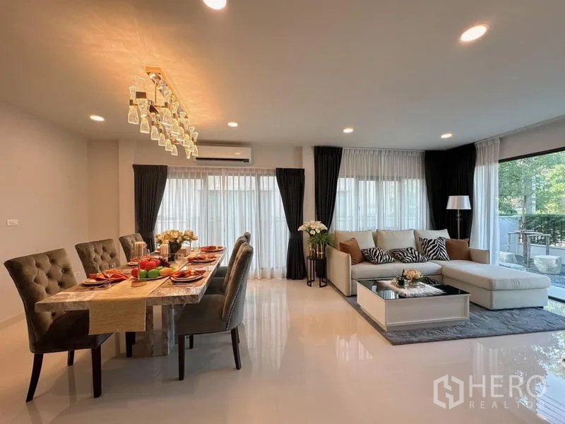 Detached House for rent or sale in Bang Phli, Samut Prakan - Open-plan living and dining area with marble table, chandelier and full-height windows.