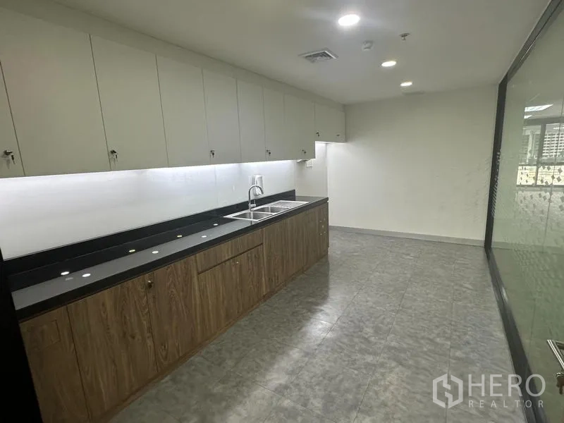 Office Space for rent in Khlong Toei, Bangkok - Office pantry with long countertop, sink, overhead cabinets and under-cabinet lighting.