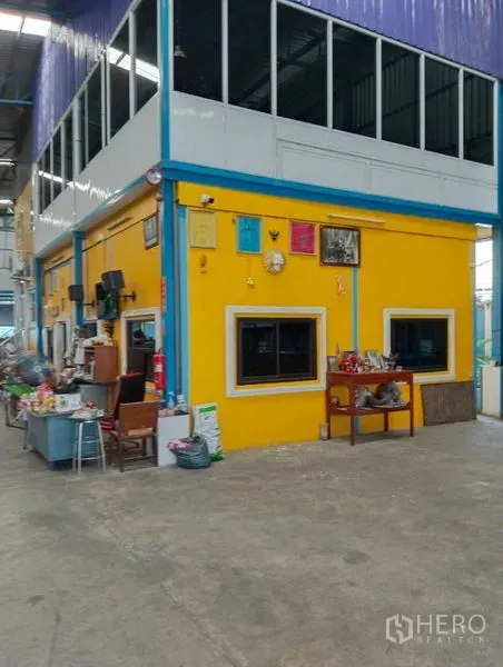 Warehouse for sale in Sai Noi, Nonthaburi - Two-storey internal office block with bright yellow facade and windows inside the warehouse.