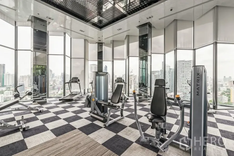 Condominium for rent or sale in Khlong Toei, Bangkok - Skyline-view fitness room with cardio and weight machines in a glass-walled gym.