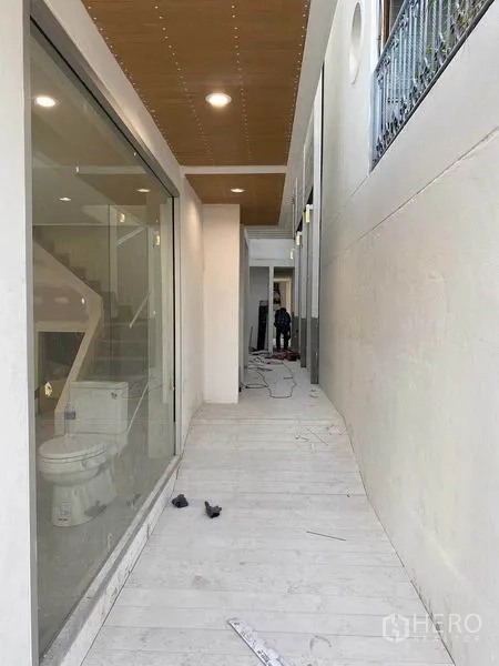 Home Office for rent in Phra Khanong, Bangkok - Covered side walkway with full‑height glass wall, wood ceiling panels and recessed lighting.