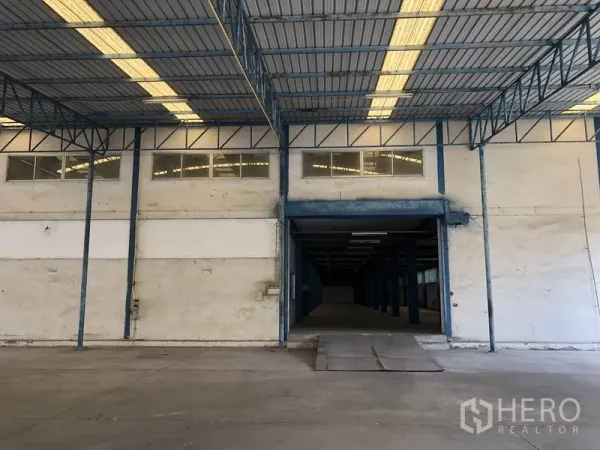 Factory for rent in Sai Noi, Nonthaburi - Wide loading entrance with ramp under a metal roof, suitable for truck access.