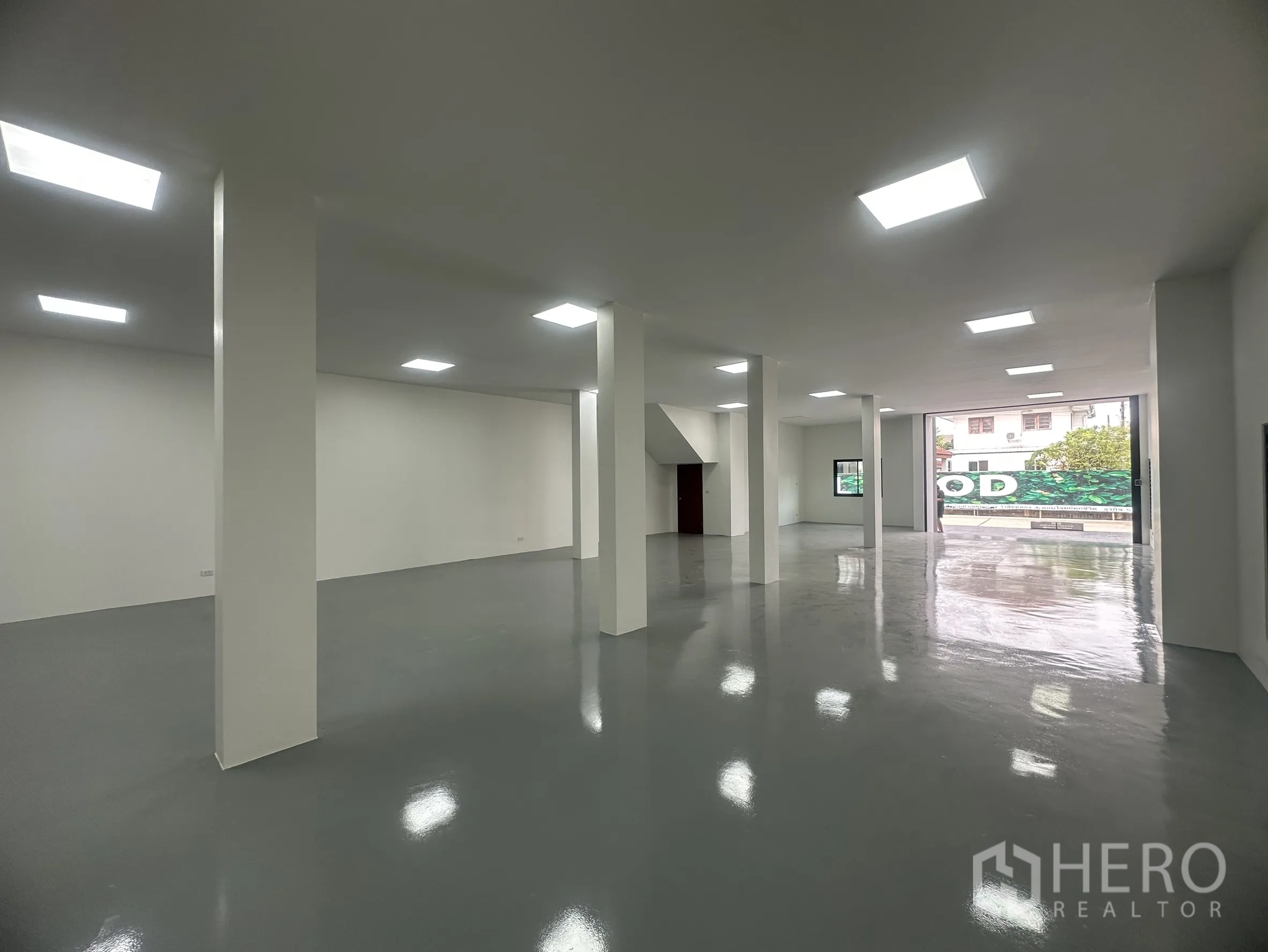 Warehouse for sale in Khlong Luang, Pathum Thani - Open-plan storage area with glossy epoxy floor and a wide roller shutter opening to the loading forecourt.