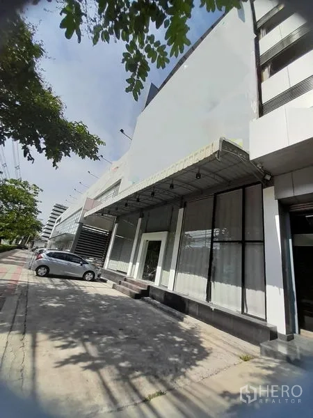 Shophouse for rent in Huai Khwang, Bangkok - Street-facing shophouse facade with wide glass storefront, canopy and parking bays.