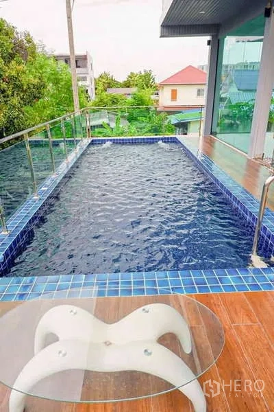 Detached House for sale in Lat Phrao, Bangkok - Long lap pool on the upper deck beside a glass-walled room and small round table.