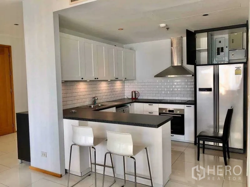 Condominium for sale in Khlong Toei, Bangkok - Modern U-shaped kitchen with white cabinets, subway tile backsplash and a breakfast bar.