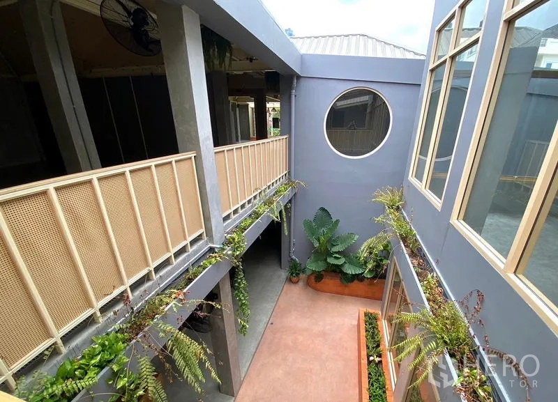 Retail Space for rent in Watthana, Bangkok - Open‑air courtyard corridor with planters, railings and a circular feature window connecting units.