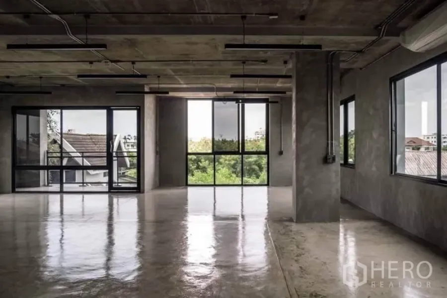 โฮมออฟฟิศ for rent or sale in Lak Si, Bangkok - พื้นที่สำนักงานเปิดโล่ง พื้นคอนกรีตขัดมัน เพดานเปิด และหน้าต่างบานใหญ่เห็นวิวต้นไม้