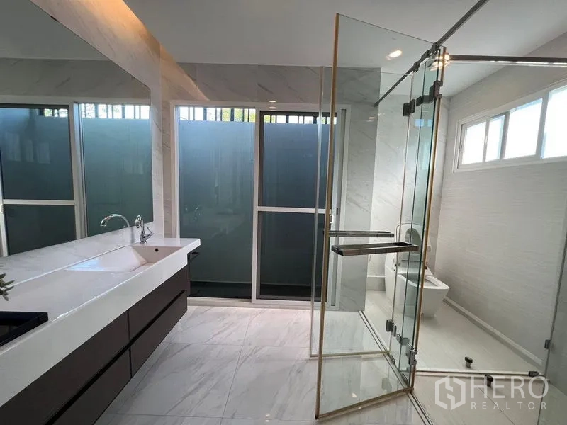 Detached House for sale - Modern bathroom with large vanity, glass shower enclosure and frosted windows for privacy.
