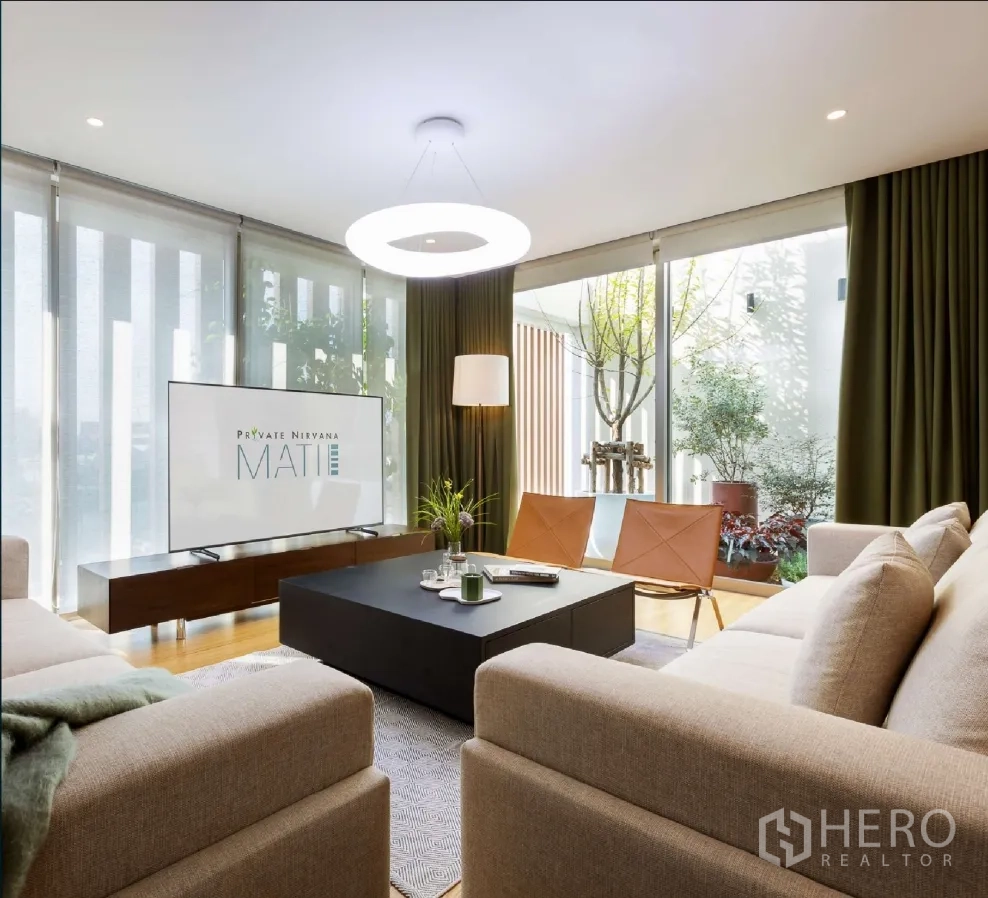 Home Office for rent or sale in Bang Khen, Bangkok - Bright living lounge with sofas, coffee table, TV console, and floor-to-ceiling glass opening to greenery.