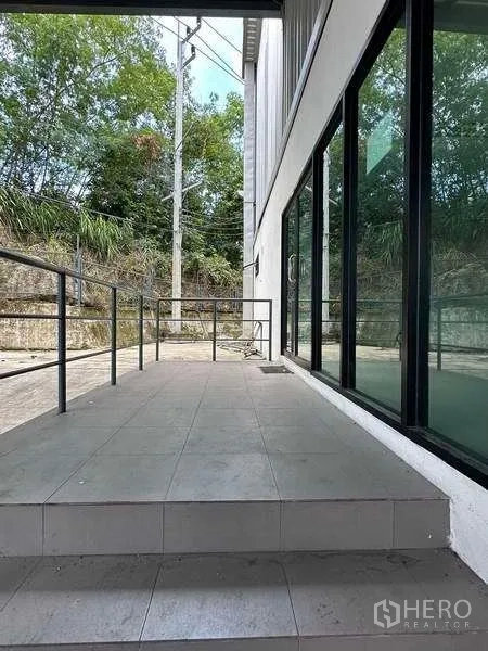 Warehouse for rent in Si Racha, Chon Buri - Entrance walkway with glass office frontage and safety railing at the warehouse.