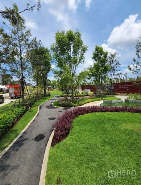 联排别墅 出租在Bang Phli, Samut Prakan - 社区景观花园，蜿蜒步道、草坪与乔木成荫。
