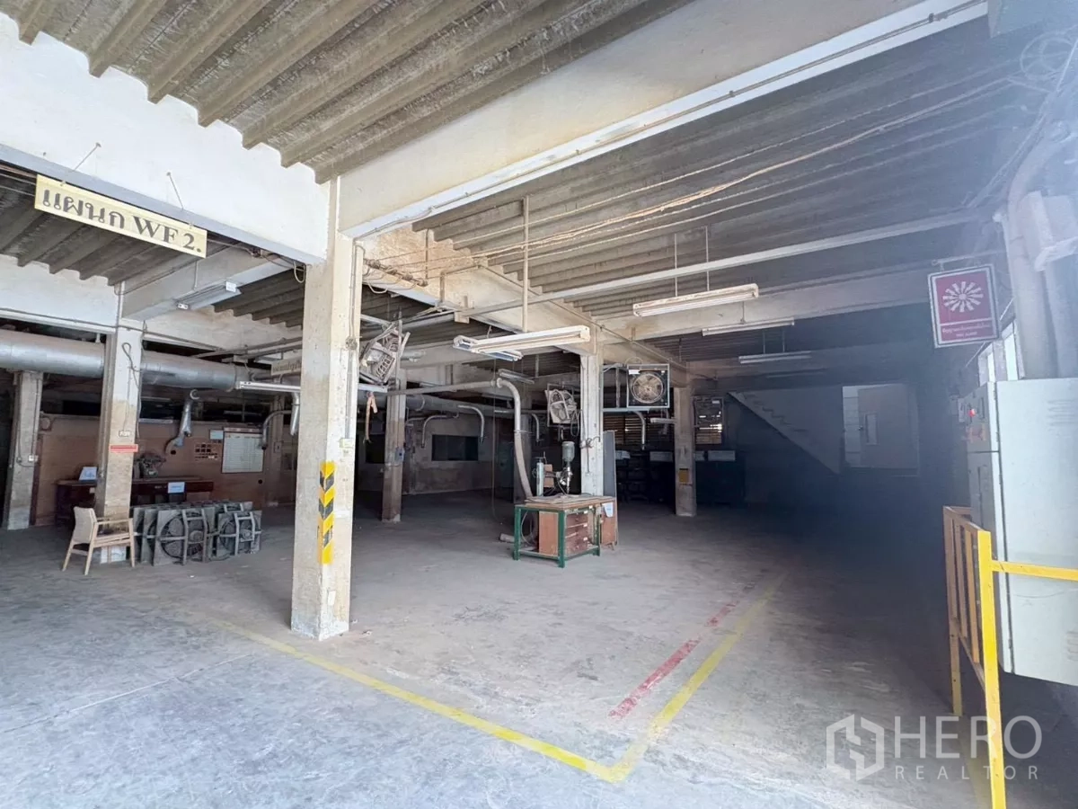 Factory for rent or sale in Bang Khun Thian, Bangkok - Open plan workspace with concrete columns, overhead lighting and stair access.